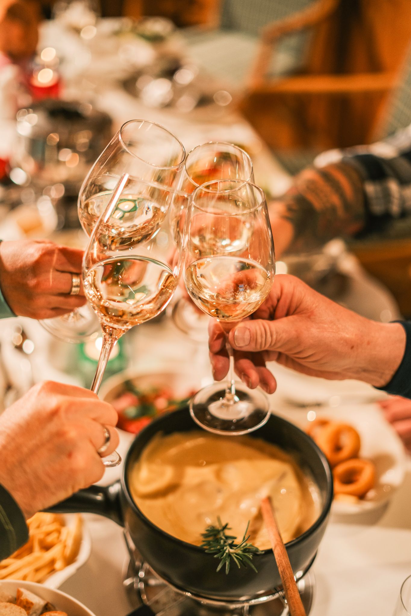 Ein fröhliches Festessen mit Fondue und Gläsern in Glemmtalerhof in Hinterglemm.