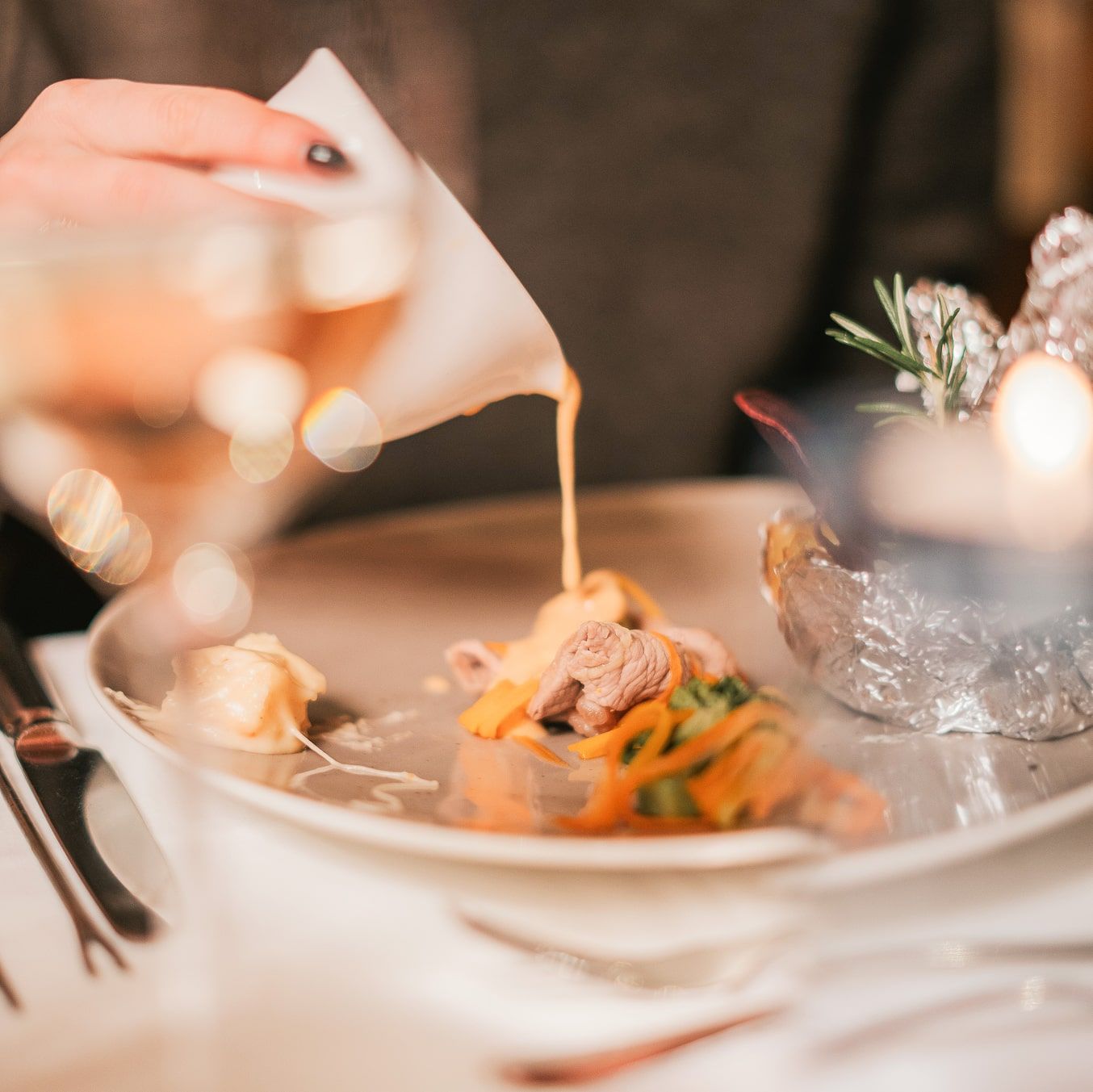 Eine Hand gießt eine Sauce auf einen Teller im Glemmtalerhof in Hinterglemm.