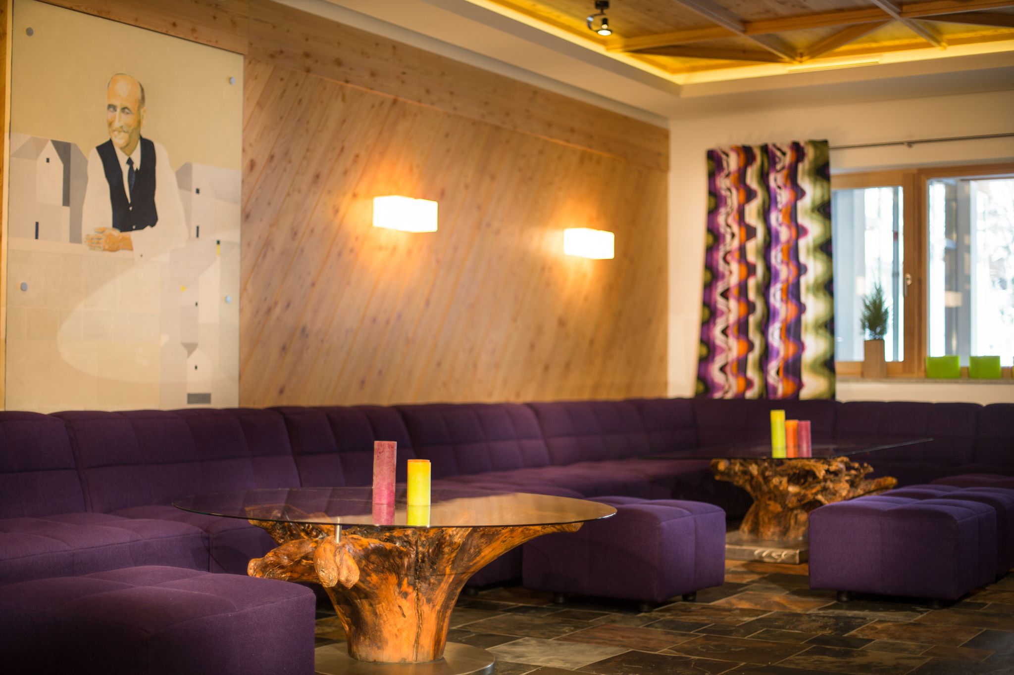 Ein modernes Wohnzimmer im Glemmtalerhof, mit lila Sofa und Holz-Dekor.