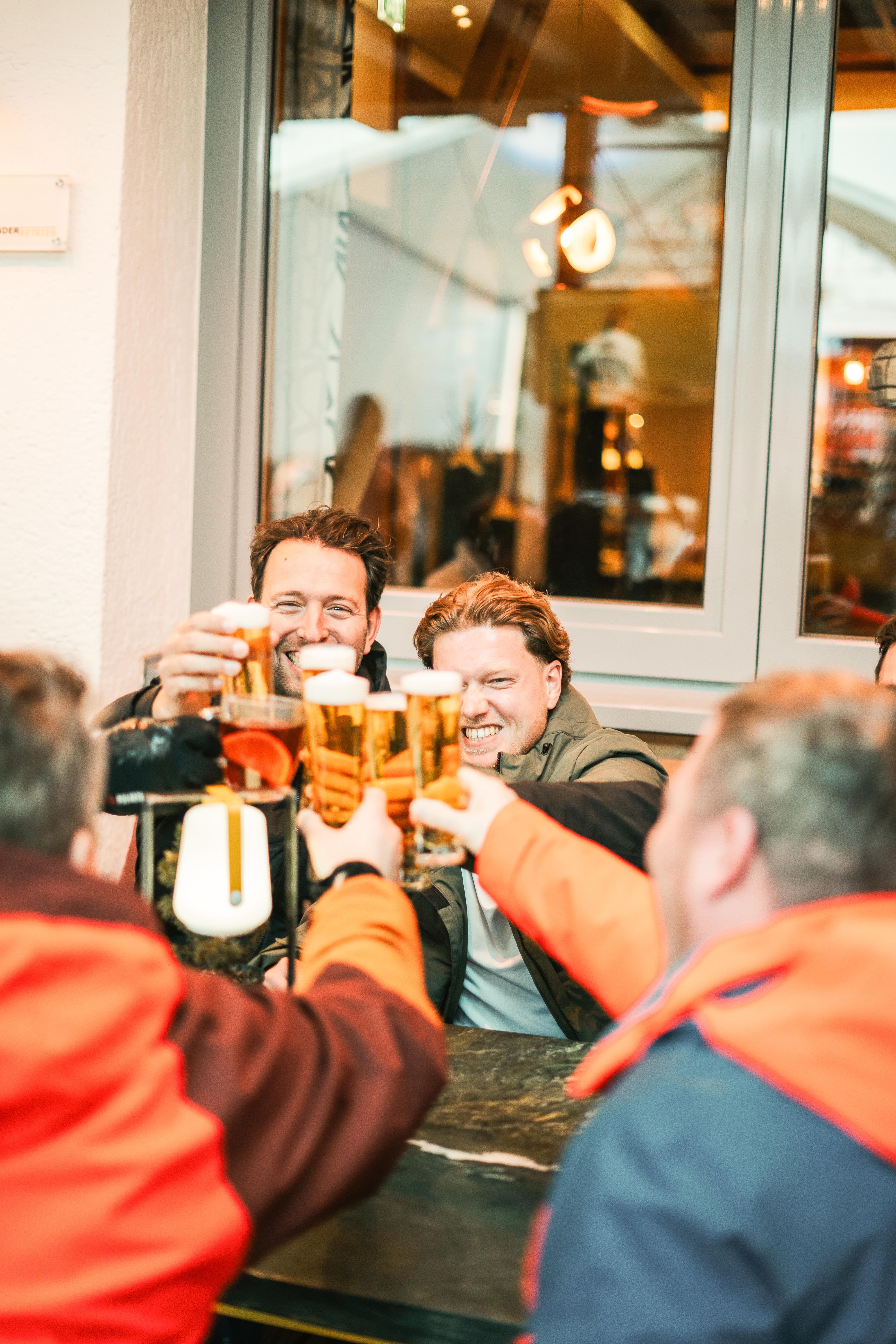 Freunde stoßen fröhlich im Glemmtalerhof in Hinterglemm an.
