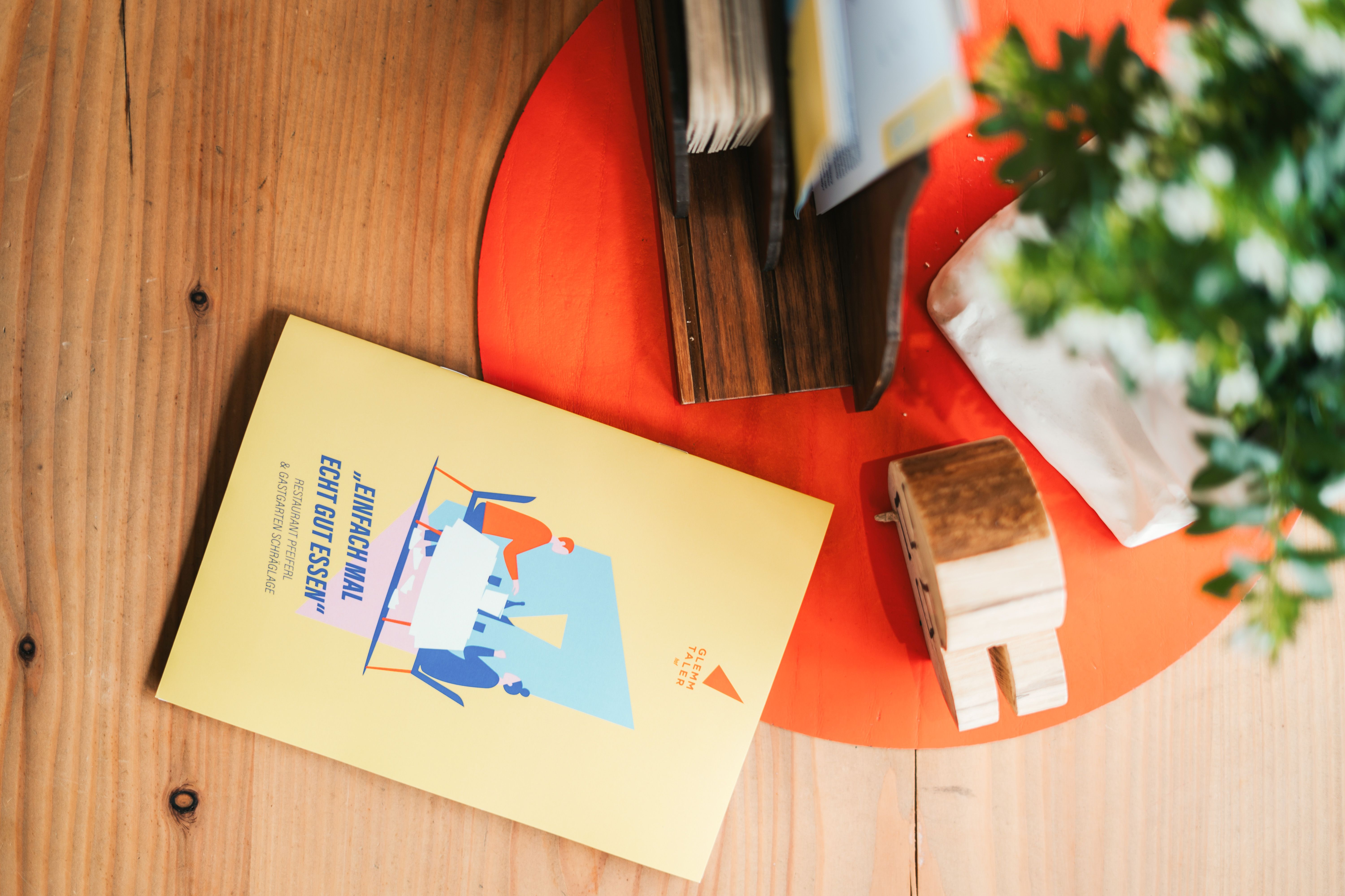 Ein farbenfrohes Menü des Glemmtalerhofs in Hinterglemm liegt auf einem Holztisch.