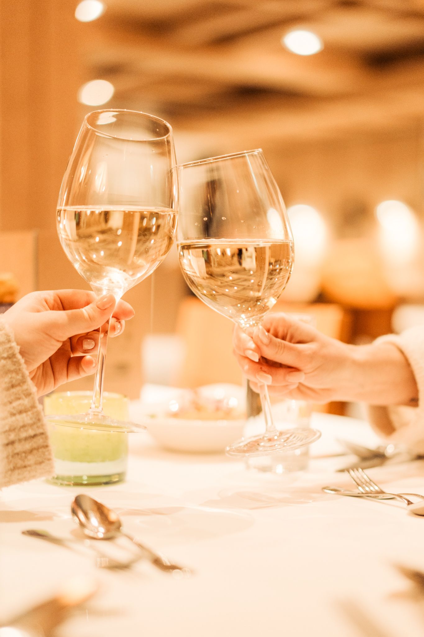 An einem Tisch im Glemmtalerhof in Hinterglemm stoßen zwei Personen mit Gläsern an.