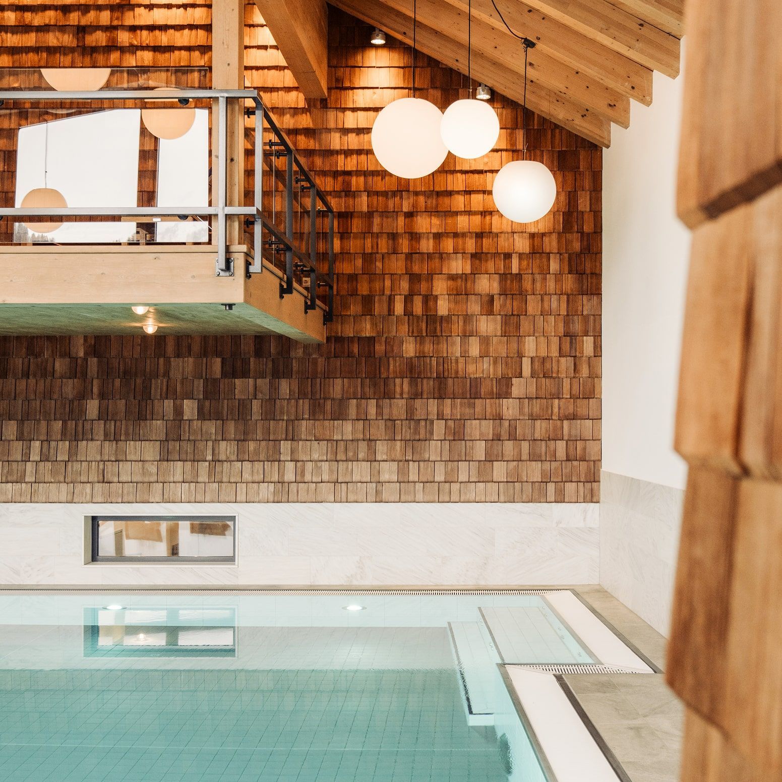 Ein eleganter Poolbereich im Glemmtalerhof in Hinterglemm mit Holzverkleidung und stilvollen Lampen.
